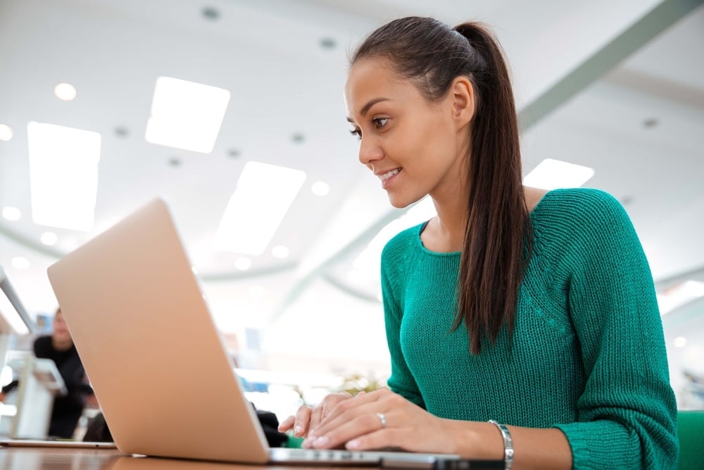 Portrait of a happy female student using laptop computer in university