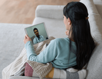 woman sitting on couch talking to virtual doctor