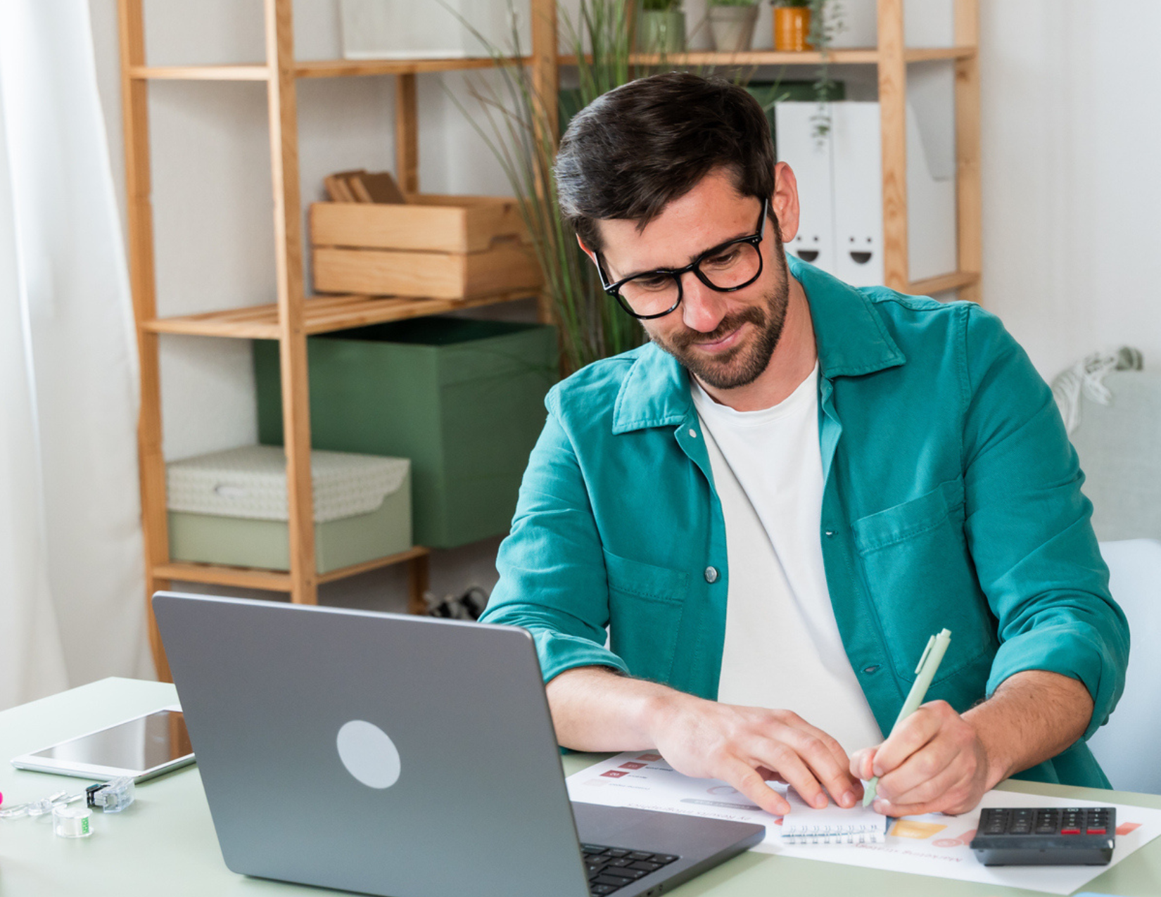 Man taking notes during telemedicine video appointment on lapop